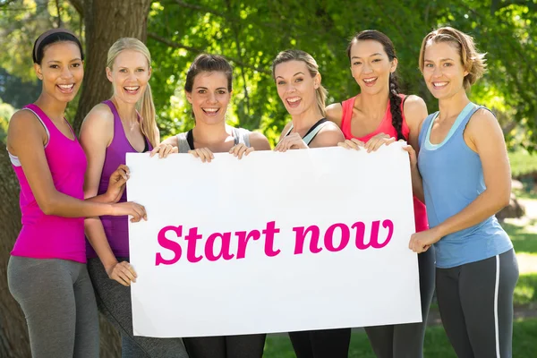 Fitness group holding poster in park — Stock Photo, Image