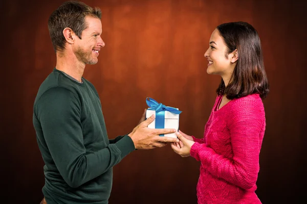 Bileşik görüntü gülümseyen çift hediye kutusu holding — Stok fotoğraf