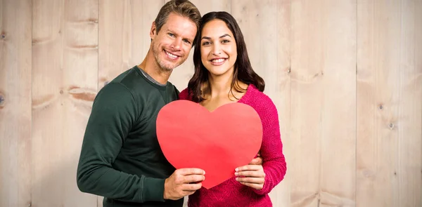 Imagen compuesta del retrato de una pareja sonriente sosteniendo el shap del corazón —  Fotos de Stock