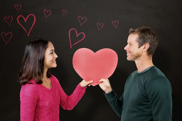 Sonriente pareja sosteniendo rojo corazón forma — Foto de Stock