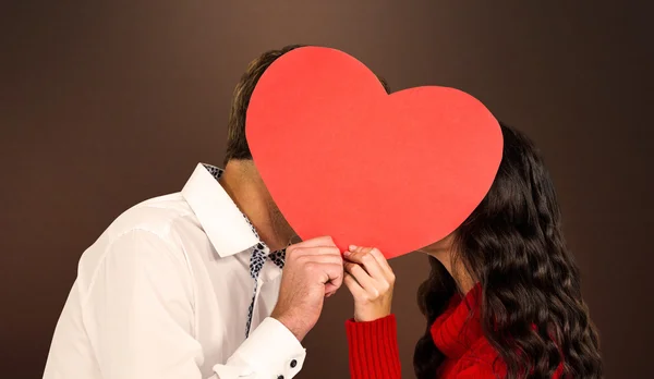 Paar die betrekking hebben op gezichten met papier hart — Stockfoto