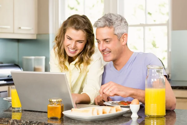 Pareja usando el ordenador portátil y desayunando —  Fotos de Stock