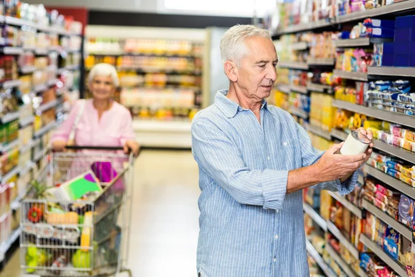 Hombre mayor mirando comida enlatada —  Fotos de Stock