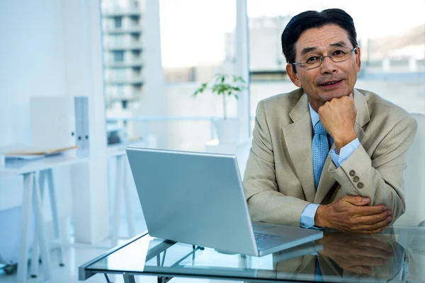 Lachende Aziatische zakenman die op laptop werkt — Stockfoto