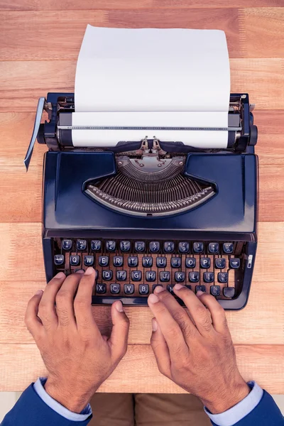 Businessman typing on typewriter at wooden desk — Stock Photo, Image