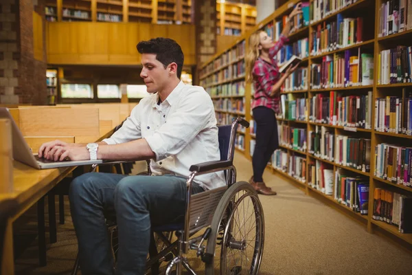 Estudiante en silla de ruedas escribiendo en su portátil — Foto de Stock