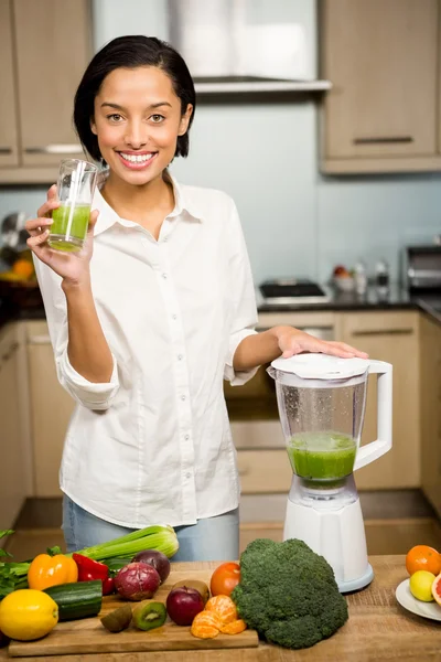 Smiling brunette holding glass of smoothie — Stock Photo, Image