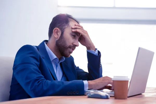 Uttråkad man som arbetar på laptop i office — Stockfoto