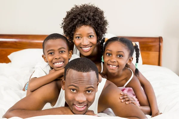 Família feliz deitada na cama juntos — Fotografia de Stock