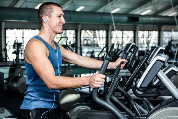 Muscular man using elliptical machine — Stock Photo, Image