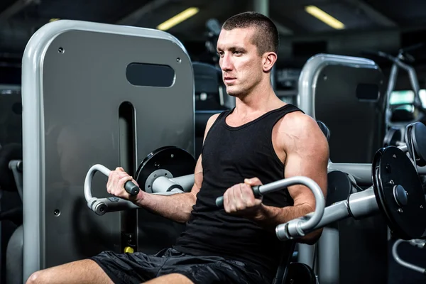 Hombre muscular usando máquina de ejercicio — Foto de Stock