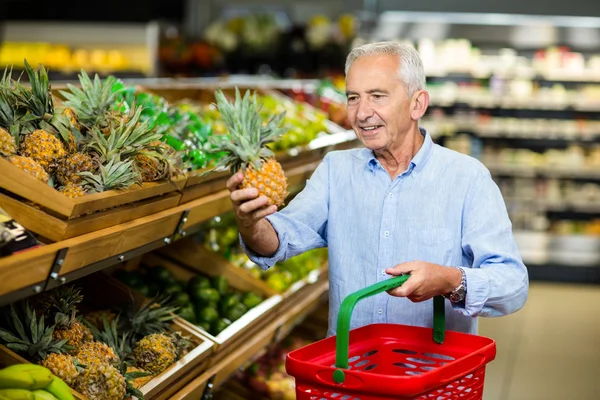 Smiling senior man picking pineapple — Stock Fotó