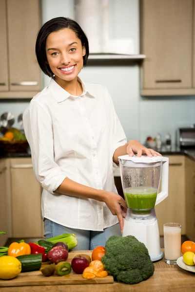 Leende brunett förbereder smoothie — Stockfoto