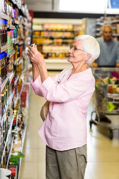 Femme âgée prenant une photo du produit sur l'étagère — Photo