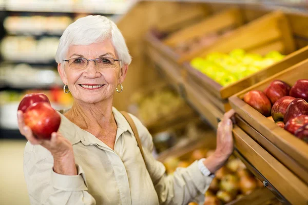 Starszy kobieta wybierając czerwone jabłko — Zdjęcie stockowe