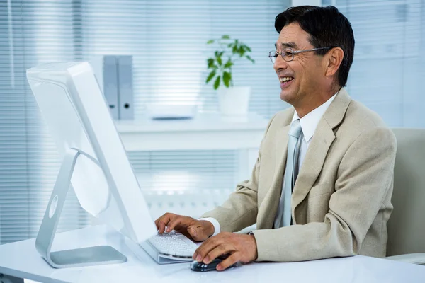 Smiling businessman using his computer — Stock Photo, Image