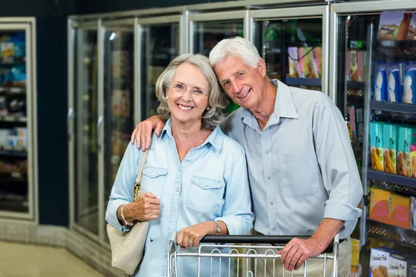 Smiling senior couple with cart — Stock Photo, Image