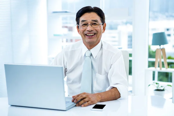Uśmiechający się azjatycki biznesmen działa na laptopie — Zdjęcie stockowe