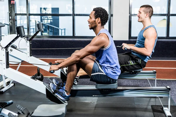 Hombres musculares usando máquina de remo — Foto de Stock