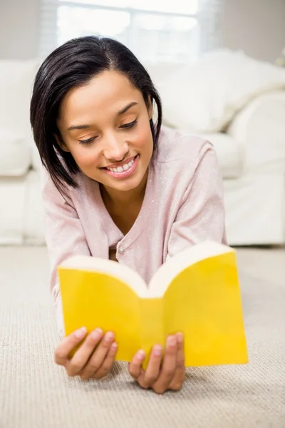 Leende brunett läser en bok — Stockfoto