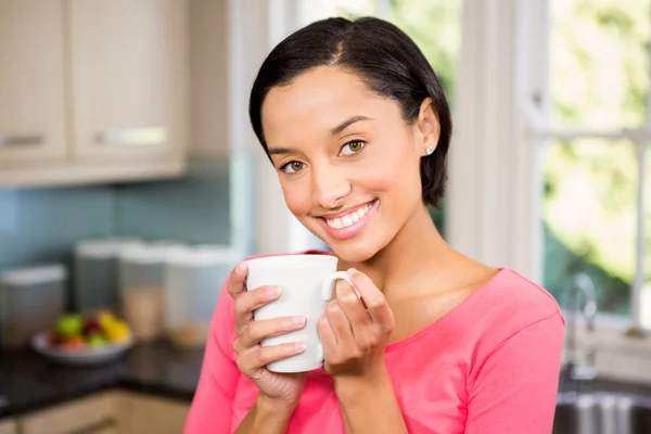 Sonriente morena sosteniendo taza blanca — Foto de Stock