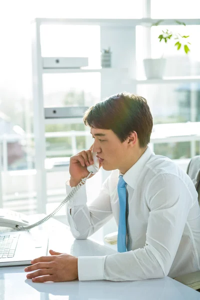 Зайнятий азіатський бізнесмен, відповідаючи на телефон — стокове фото