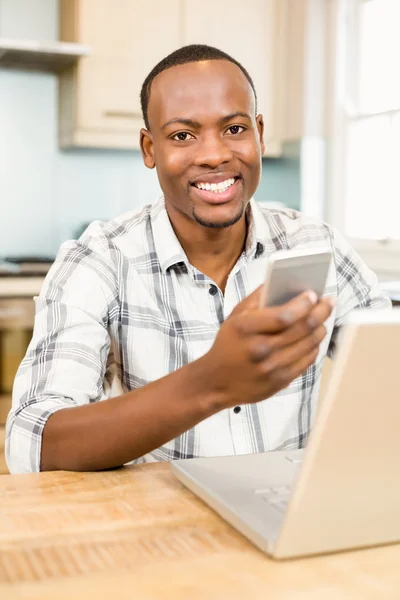 Handsome man holding smartphone in kitchen — Stock Photo, Image
