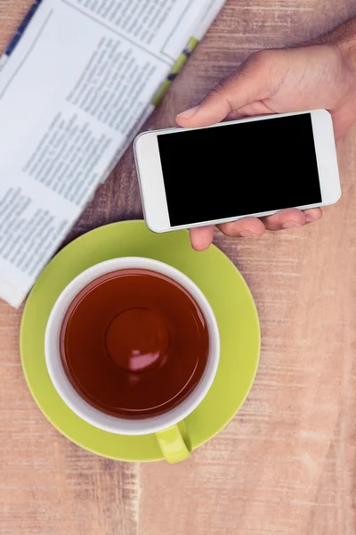 Man bedrijf smartphone door koffie — Stockfoto