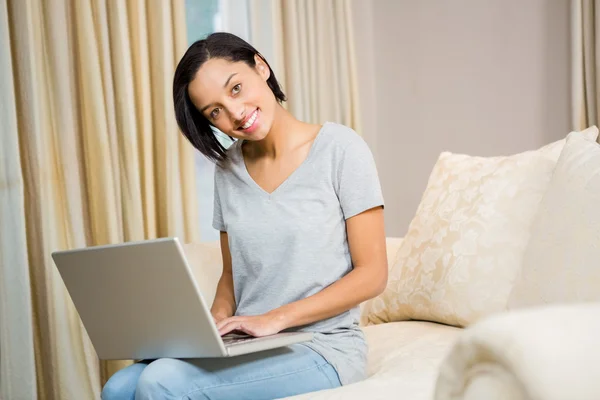 Lachende brunette met behulp van laptop — Stockfoto