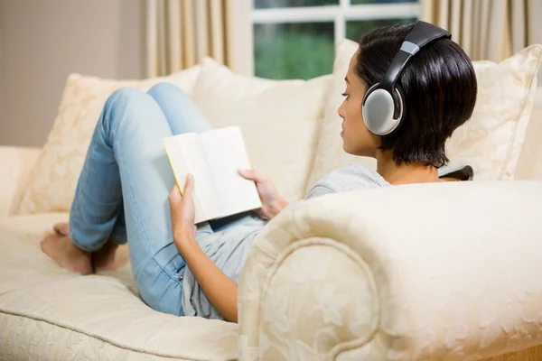 Morena com fones de ouvido lendo um livro — Fotografia de Stock