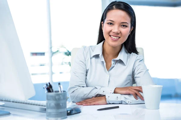Confident businesswoman sitting on desk posing for camera — Stock Photo, Image