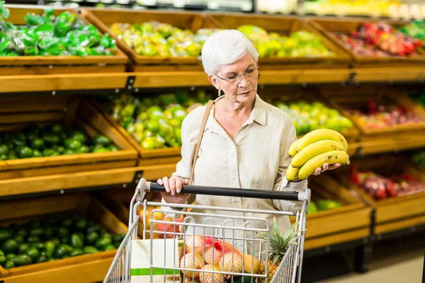 Senior vrouw banaan aanbrengend haar trolley — Stockfoto