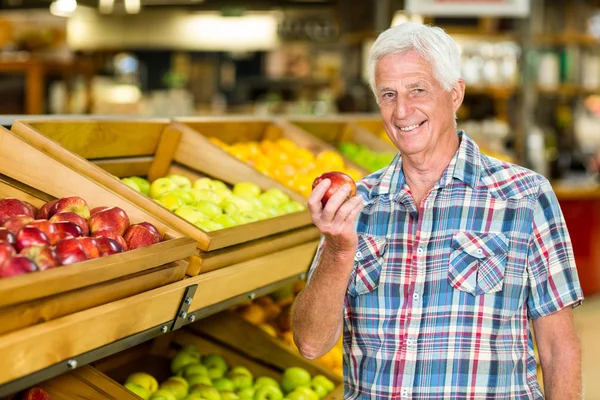 Homme âgé souriant tenant une pomme — Photo