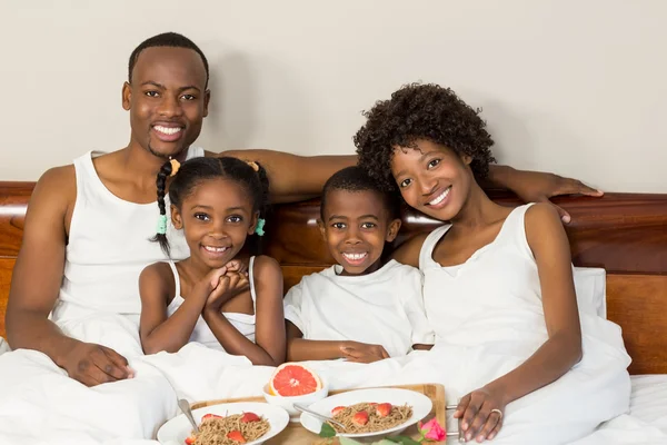 Familia feliz acostada en la cama juntos — Foto de Stock