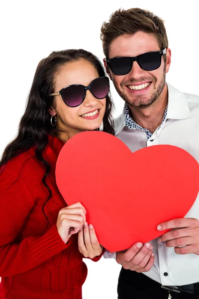 Smiling couple with sunglasses holding paper heart — Stock Photo, Image