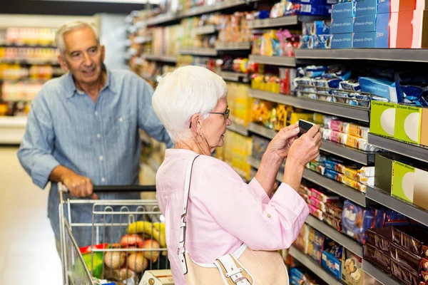 Femme âgée prenant une photo du produit sur l'étagère — Photo