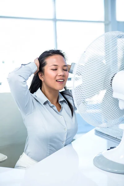 Businesswoman sitting in front of fan — Stock Photo, Image