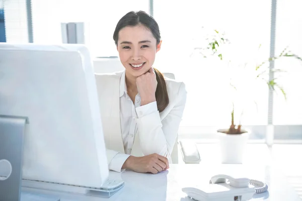 Uśmiechnięta kobieta pracuje na jej biurku — Zdjęcie stockowe