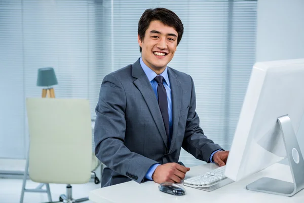 Empresário sorridente usando seu computador — Fotografia de Stock