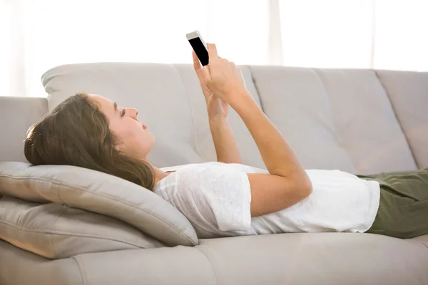 Mulher segurando telefone no sofá — Fotografia de Stock