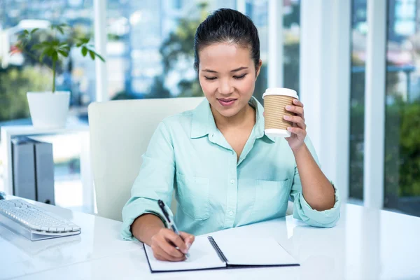 Lächelnde Geschäftsfrau schreibt Notizen — Stockfoto