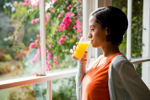 Przemyślane brunetka picie soku pomarańczowego — Zdjęcie stockowe
