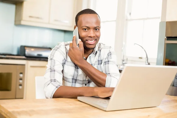 Homme utilisant un ordinateur portable et ayant un appel téléphonique — Photo