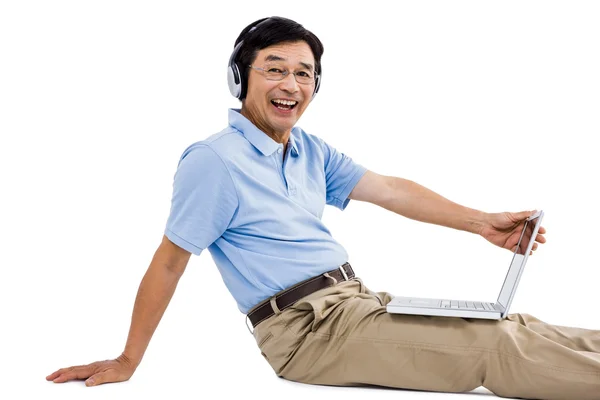 Retrato de homem alegre usando laptop enquanto ouve música — Fotografia de Stock
