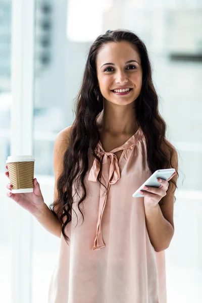 Kvinna med smartphone holding disponibel cup — Stockfoto