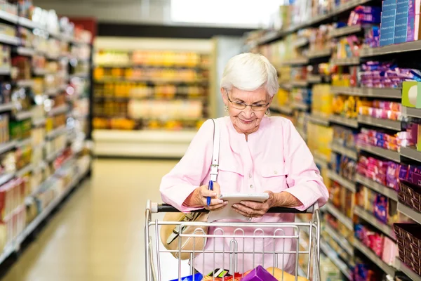 Старшая женщина смотрит на свой список покупок — стоковое фото