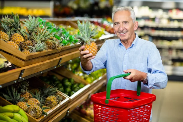 Smiling senior man picking pineapple — Stock Fotó