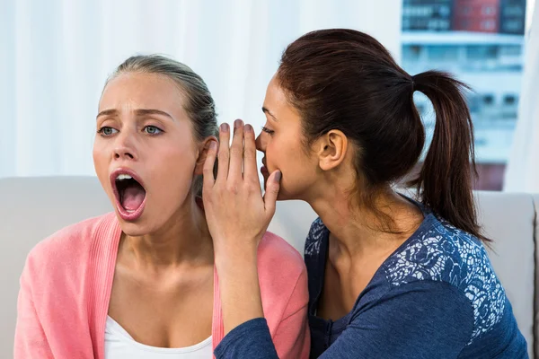 Friends telling secrets on sofa — Stock Photo, Image