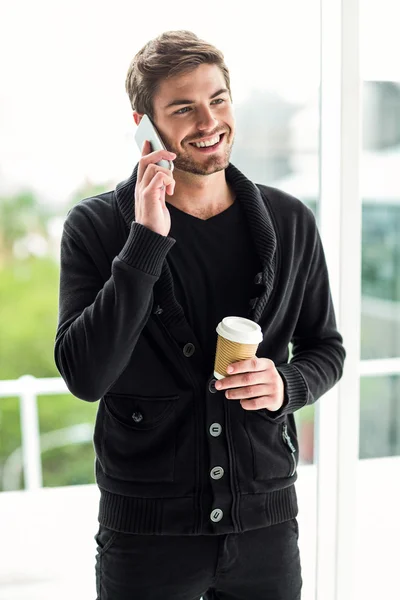 Hombre guapo en la llamada telefónica sosteniendo taza desechable —  Fotos de Stock