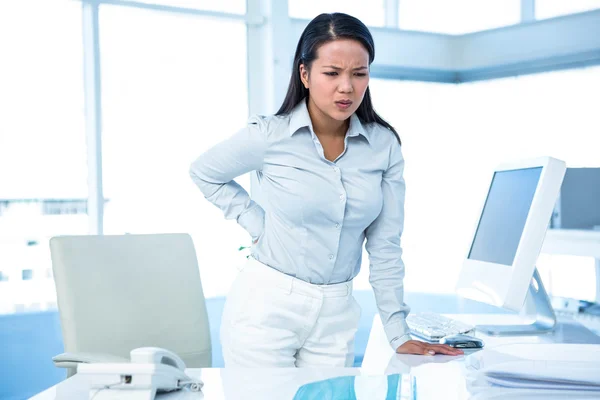 Stirnrunzeln bei Geschäftsfrau mit Rückenschmerzen — Stockfoto